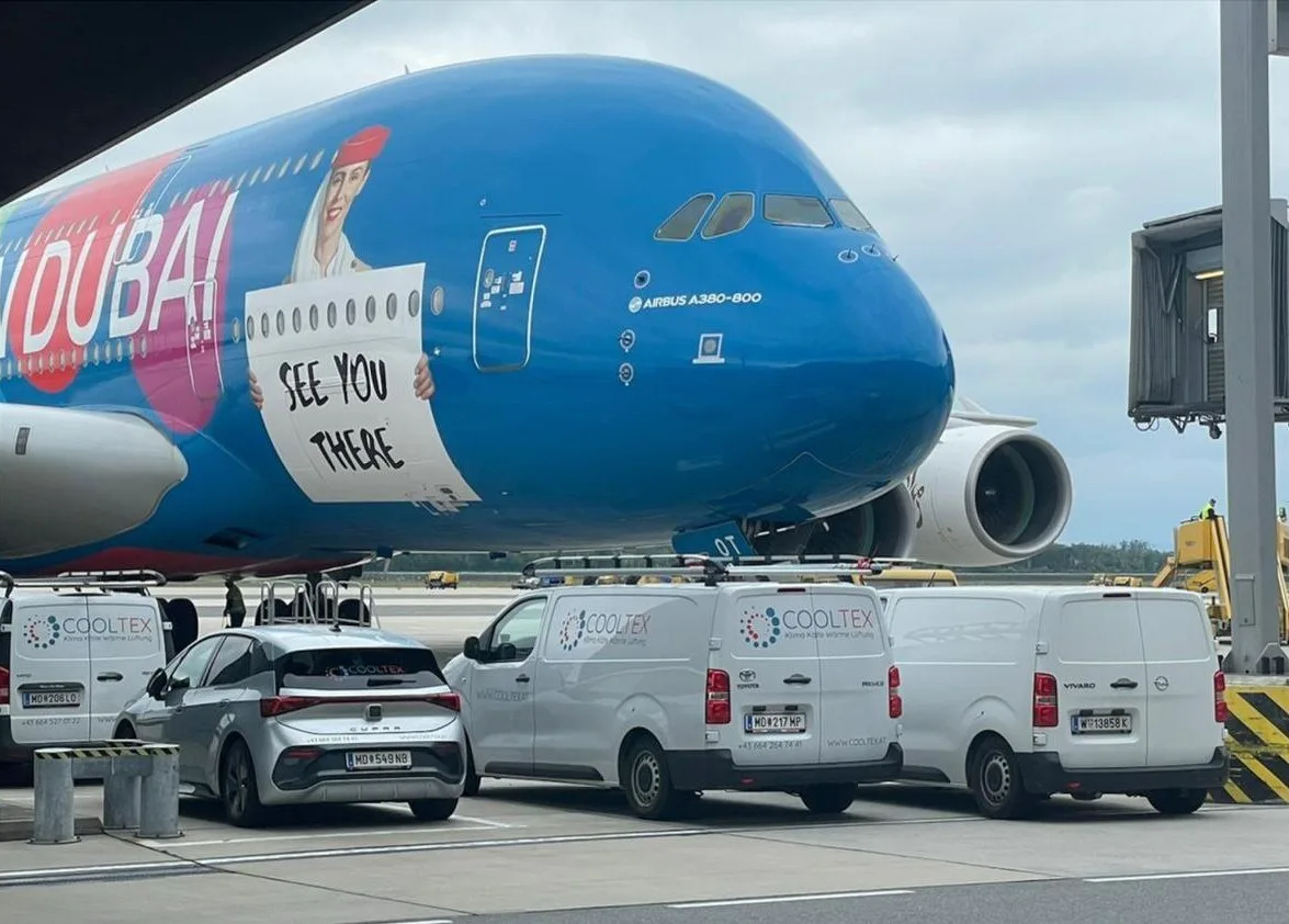 Drei weiße Cooltex-Servicewagen auf einem Flughafenvorfeld, dahinter ein Verkehrsflugzeug