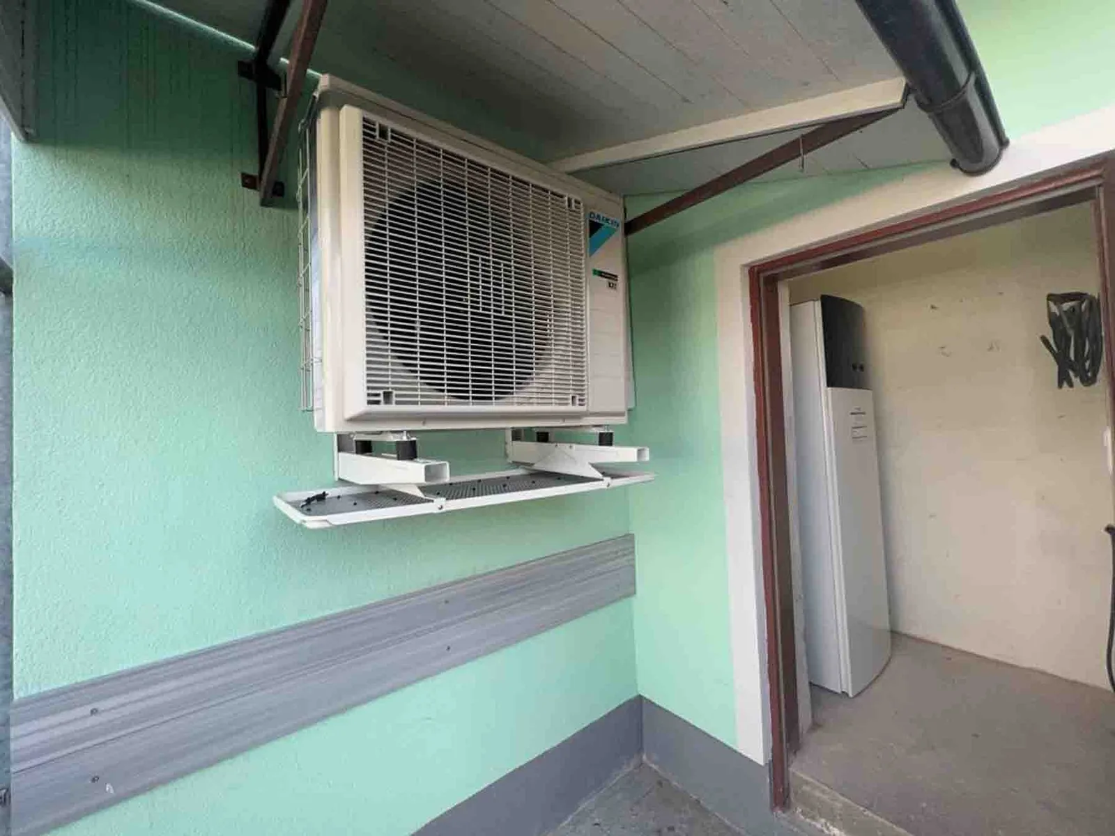 Daikin-Außengerät an einer Wandkonsole, daneben die Inneneinheit