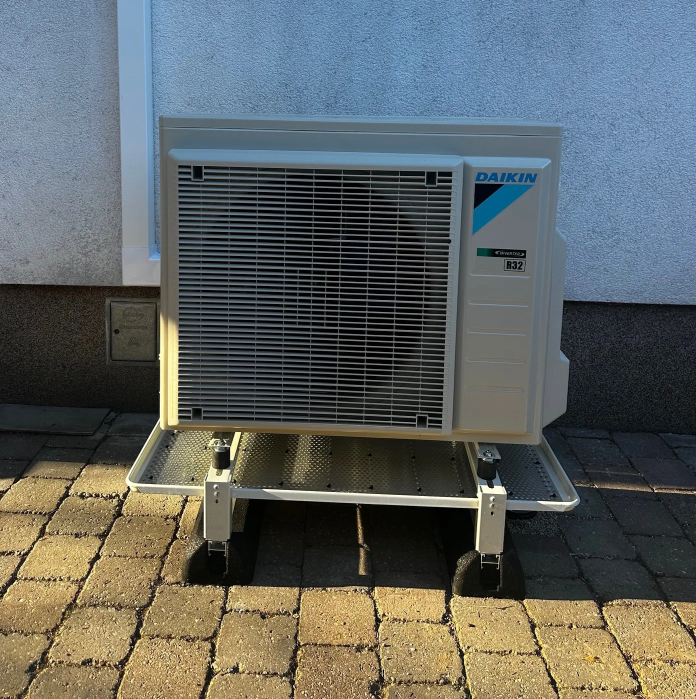 Daikin-Außengerät auf einem Gestell vor einer Hausmauer