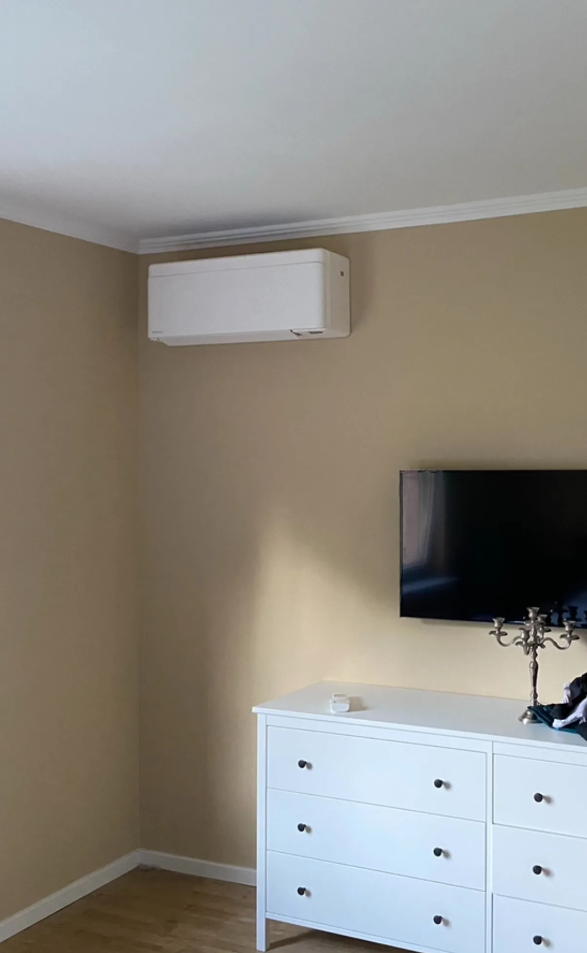 Weißes Wand-Innengerät einer Klimaanlage in einem Schlafzimmer über einer Kommode